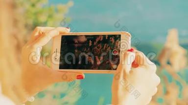 年轻女子用智能手机在湖岸拍摄风景视频。 红色摄像机拍摄